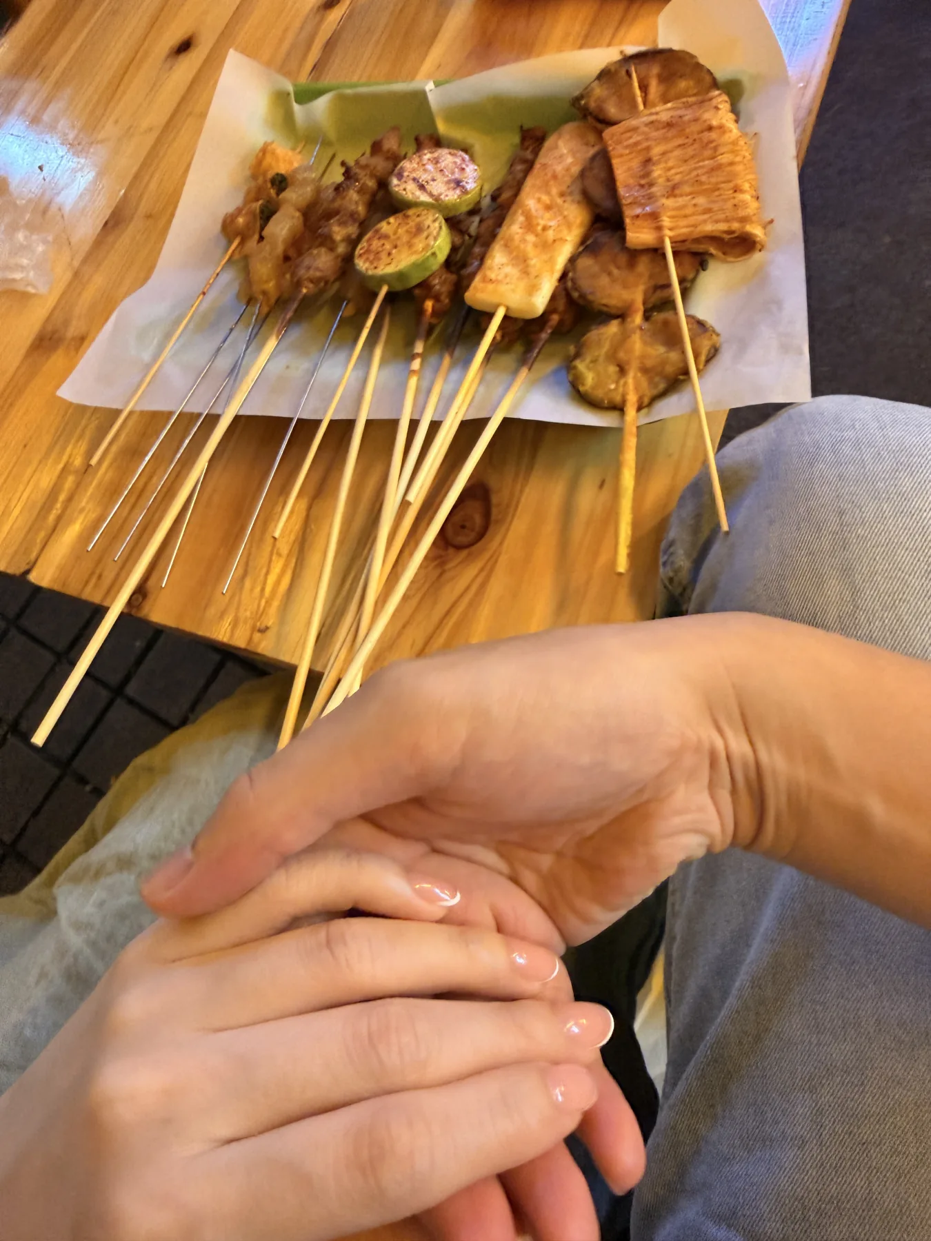路边烧烤串和两个人牵着手的照片